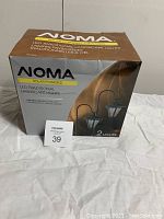 Boxed NOMA LED traditional landscape lights, two lights per box, solar powered, with manufacturer branding and product details on the box.