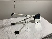 Side view of the trailer towing mirror showing the telescoping adjustable white metal arms with clamps at the ends and rectangular black framed mirror surface.