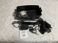 Full lot including Conair Turbo hair clippers, length attachments, power adapter, and black plastic storage case missing cover, all displayed on white fabric.