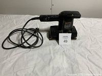 Side view showing the entire Black & Decker electric sander with power cord, resting on white cloth backdrop.