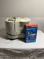 Side view of the Honeywell QuietCare humidifier showing main unit and a box of replacement humidifier filter labeled Model E