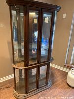 Front view of large wood framed glass curio cabinet with double glass doors and mirror back.