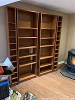 Front view of both wooden shelving units side by side against a wall near a stove, showing all shelves and structure.