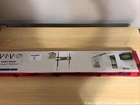 Long box packaging showing brand VIVO and model VW100, with image of TV mount and storage setup.