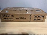 Closed original shipping box labeled VIVO STAND-V002L with product info and VESA compatibility.