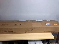 Photo of the cardboard packaging box with seller brand and product name showing 'VIVO STAND SHELF46B Clamp-on 46" Shelf Monitor Riser' printed on the side.