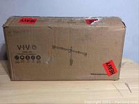 Closed cardboard box labeled VIVO with triple monitor stand model STAND-V103 with visible heavy label and basic product illustration.