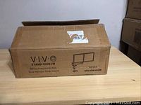 Closed original cardboard box labeled VIVO STAND-V002JW showing product name and basic graphics of dual monitor mount.
