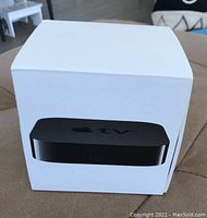 White Apple TV box displaying the image of the Apple TV device on the front.
