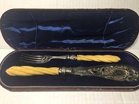 Fish serving knife and fork with bone handles in original velvet-lined wooden case.