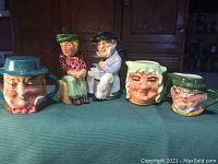Front view of five hand-painted character miniature pottery pieces featuring Dickens characters including a teapot and Toby jugs.