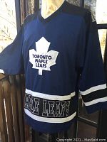 Front view of navy blue Toronto Maple Leafs hockey jersey on mannequin, showing primary logo and stylized stripes.