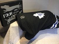 Black lightweight mesh Toronto Maple Leafs dog jersey displayed on a dog mannequin alongside a dog-themed wall hanging plaque