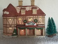 Front view of the Windsor Club building showing snow-topped red roof, lit windows, front sign, and accompanying snow-covered trees.