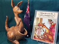 Front view of ceramic kangaroo figurine with Australian flag and Mercer Mayer book in background.