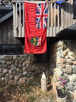 Ontario Provincial Flag hanging on wooden fence, showing full vertical length and color details.
