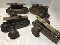 Four antique door knob sets showing ornate backplates and knobs, arranged in a group.