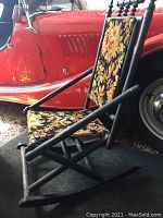 Side view of the wooden Victorian rocking chair showing floral fabric backrest and seat with turned spindle details and gently curved wooden rockers.