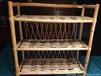 Full view of the three-tier bamboo and wicker shelf showing the woven shelves and bamboo frame