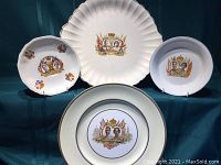 Four commemorative plates shown together with visible portraits of King George VI and Queen Elizabeth, various decorative flag and crown motifs, white ceramic with colorful details