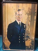 Front view of rectangular tin featuring full-length portrait of Prince Philip in naval uniform with medals.