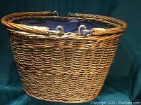 Front perspective view of the wicker picnic basket showing woven wicker, steel rim reinforcement, and handles.
