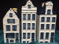 Front view of three blue and white ceramic KLM Blue Delft house decanters with yellow chimneys