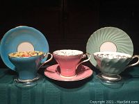 Three cups and saucers arranged side by side: blue on left, pink center, mint green right