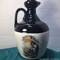 Photo of the jug showing the painted seated MacKay figure on the white lower half with black upper portion of jug including neck and handle.