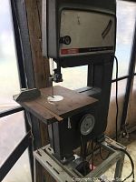 Full view of the band saw showing the table, blade, and upper housing with brand label.