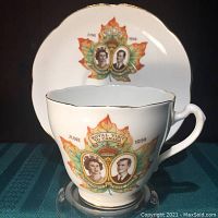 Photo of commemorative bone china teacup featuring portraits of Queen Elizabeth II and Prince Philip inside a maple leaf design with 'Royal Visit to Canada June 1959' text