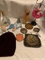 Full lot overview showing perfume bottles, compact mirrors, petits point purses, mannequin display and velvet pouch