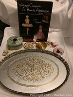 Full view of vanity tray with compacts, decorative items, and book on display.