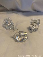 Three Swarovski crystal animal figurines displayed on a light fabric surface: a swan, a mouse, and a third animal.