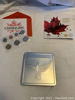 Photo of 2012 Canada uncirculated coin set, including the coins sealed in plastic pouch, a colorful informational card, and envelope with Canadian symbols