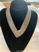 Front view of the Whiting and Davis silver toned mesh necklace displayed on a black stand.