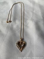 Front view of the gold heart pendant necklace with stones along one side of the heart. Chain laid flat showing pendant details.