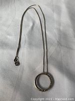 Full view of the silver infinity necklace on a white surface showing the chain and pendant.