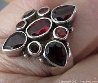 Close-up view of the top of the ring showing the seven garnet stones in various shapes set in silver bezels.