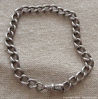 Sterling silver watch chain bracelet displayed on beige textured fabric, showing chain links and swivel clasp detail.