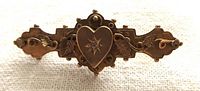 Front view of antique Victorian yellow gold locket pin showing heart with clear center stone, applied leaves, twisted wire, and beaded border.