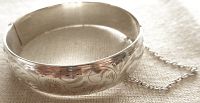Top view of the sterling silver bangle showing detailed floral engravings and polished finish.