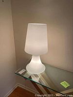 Modern frosted glass lamp on a glass table, illuminated to show the frosted diffused light.
