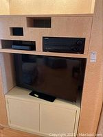 Full view of the electronics including the Vizio flat screen TV on lower shelf, Pioneer stereo receiver on top shelf, and a black device on the left upper shelf (presumed to be a speaker component).