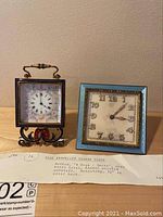 Both clocks shown together on a wooden surface with handwritten note below.