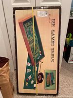 Full boxed set of the six-in-one game table showing the graphics of the game table and components included such as dice, cards, chips, and roulette wheel.