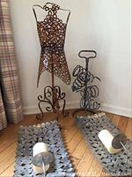 Full view of the metal decorative dress form, metal wine rack, and two metal wall sconces with candles placed on hardwood floor.