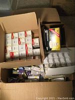 Top view of four open boxes filled with various light bulbs in original packaging, mostly white boxes with labels visible.