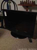 Front view of Samsung 32-inch TV on its circular stand with remote on the side.