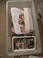 Plastic bin containing two smaller containers holding various mixed sports trading cards, some loose and some boxed.